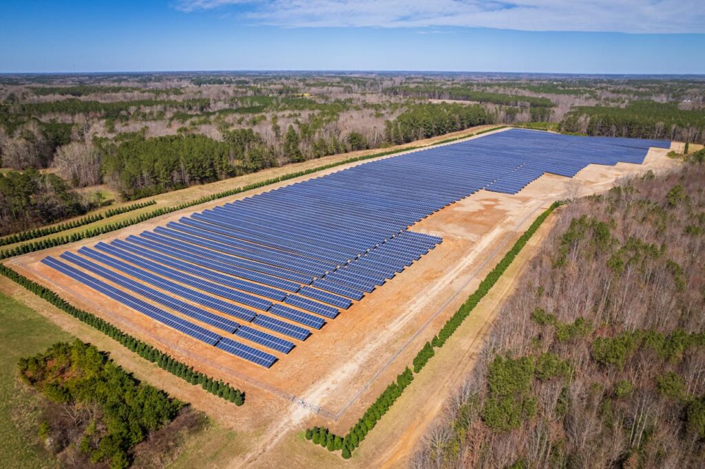 pexels-photo-15751124 Aerial drone shot of a large solar panel farm in a rural area surrounded by forests in North Carolina.